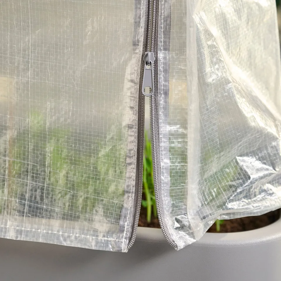 A greenhouse cover, white, made of polyethylene, with zippers for access. It protects plants from harsh weather.