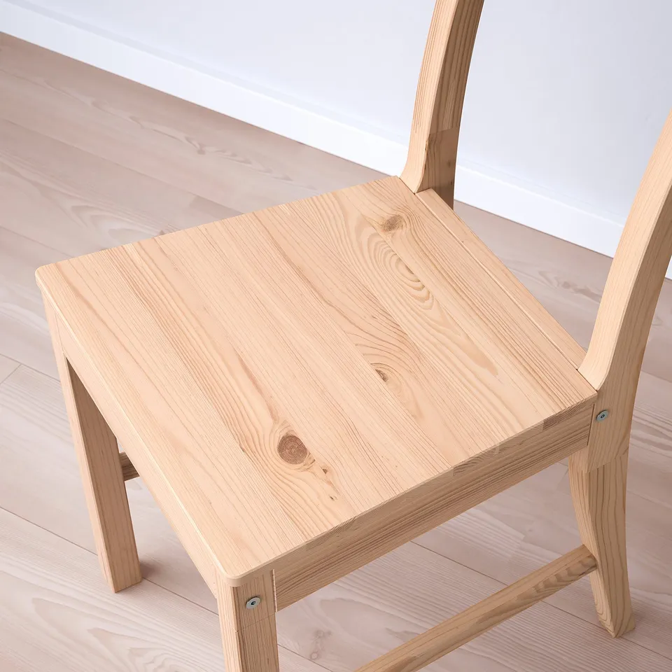Modern wooden chair with light finish, natural grains visible, sturdy design, angled backrest, and wide seat.
