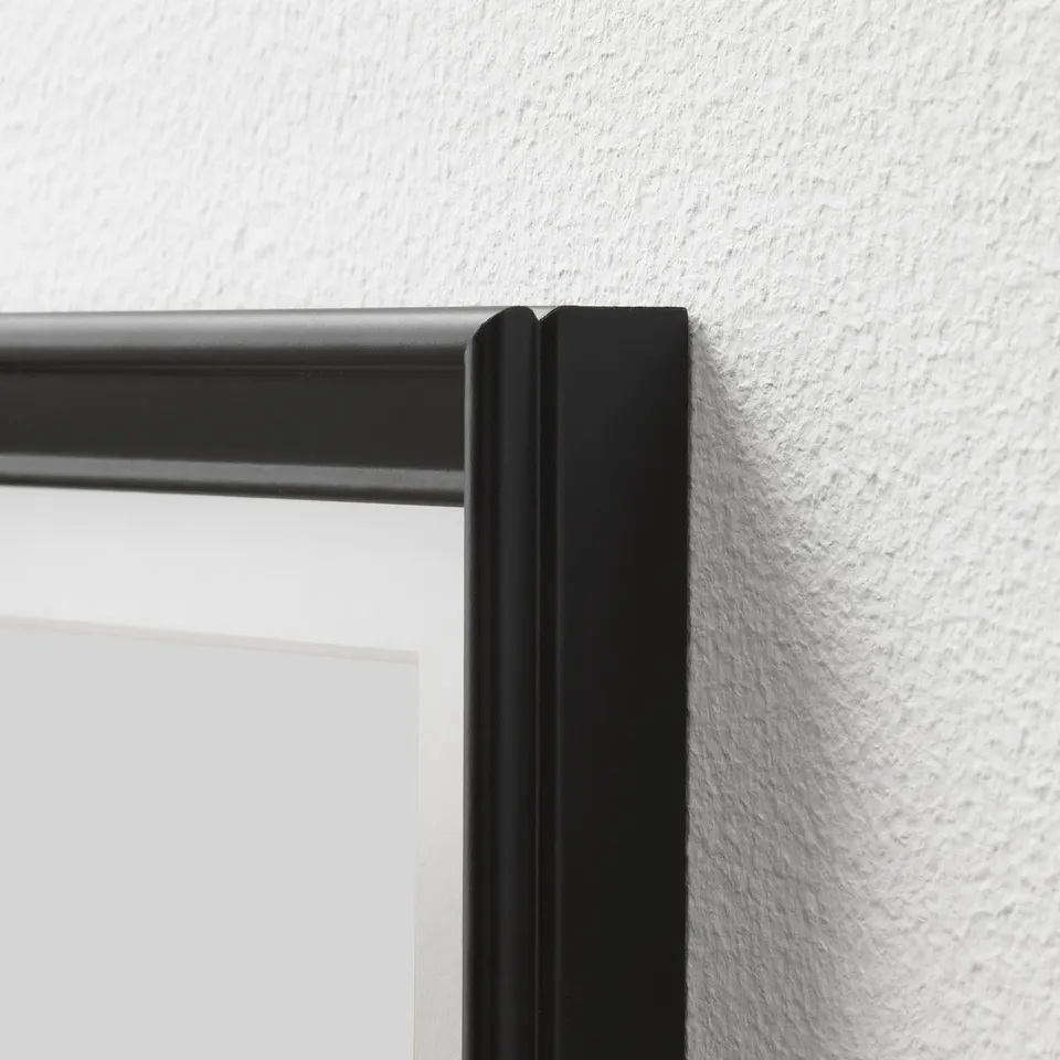 Frame detail: close-up of black picture frame corner with sleek, thin profile against white wall, highlighting quality craftsmanship.