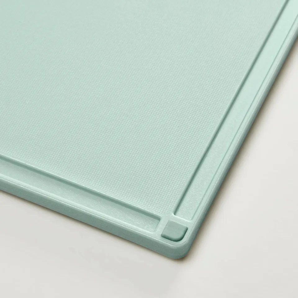Presentation of a light green, textured chopping board with non-slip edges.