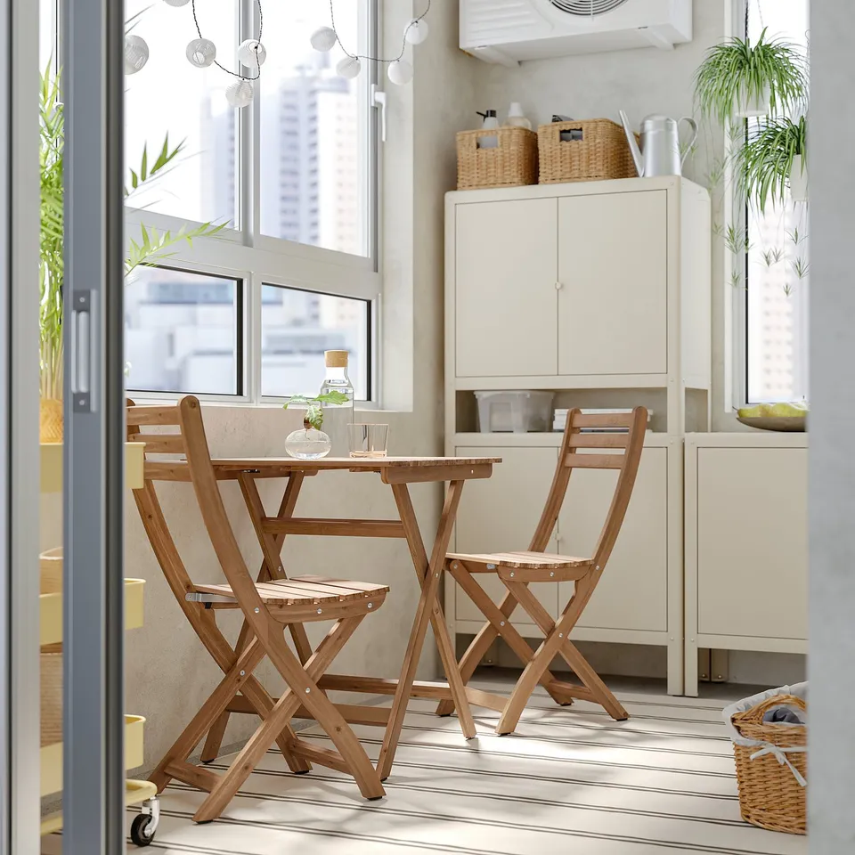 ASKHOLMEN folding outdoor dining set with table & 2 chairs, cushions, near window.