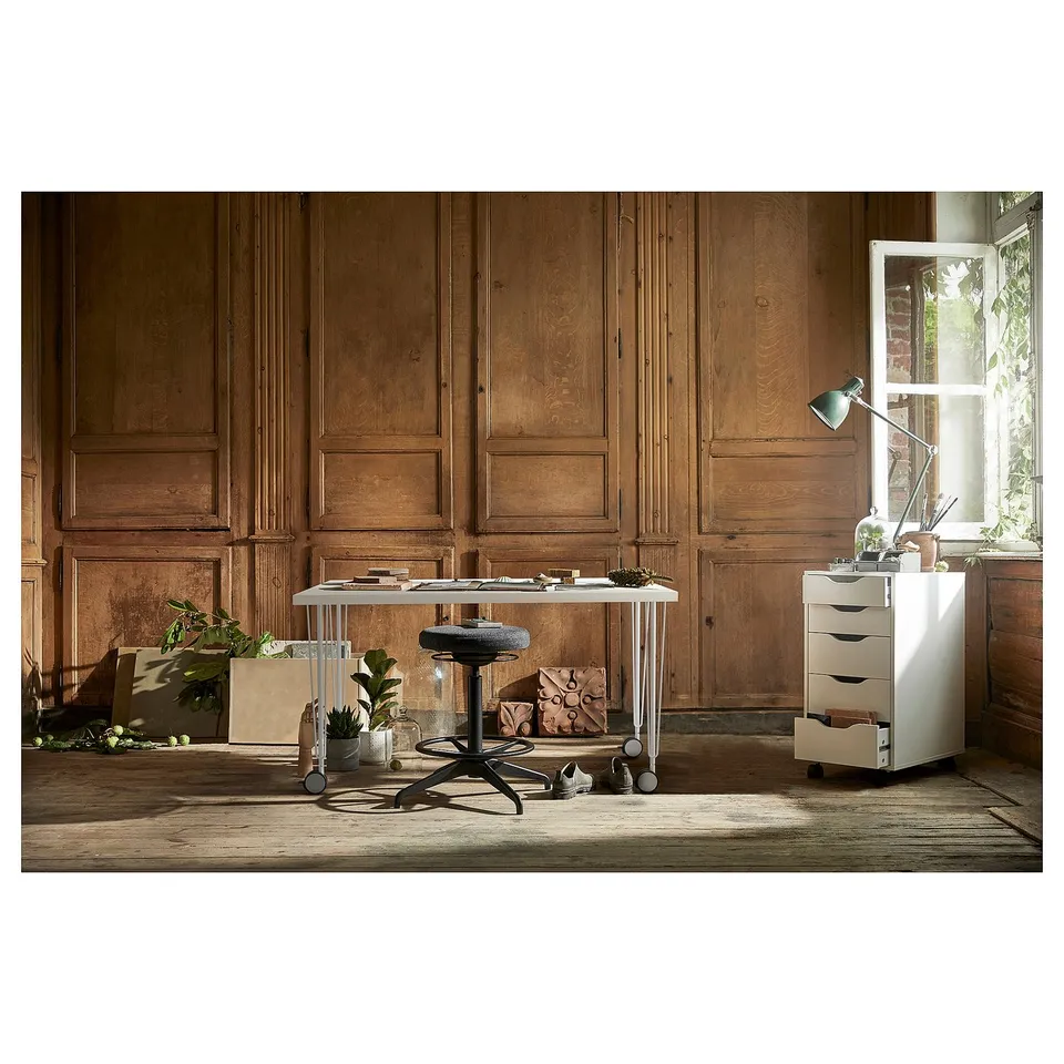 Modern home office with LAGKAPTEN desk, stool, filing cabinet, plants; wood-paneled walls & window.
