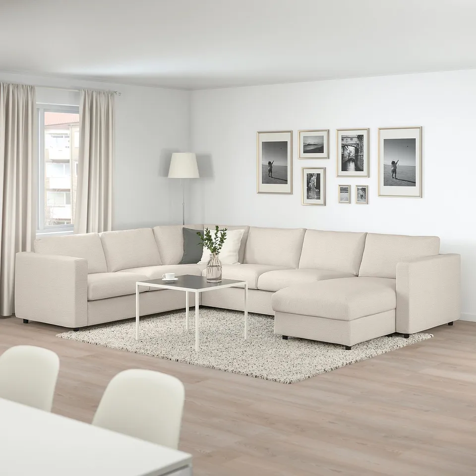 Modern living room with large beige VIMLE sectional sofa, black & white photos, and wood floor.