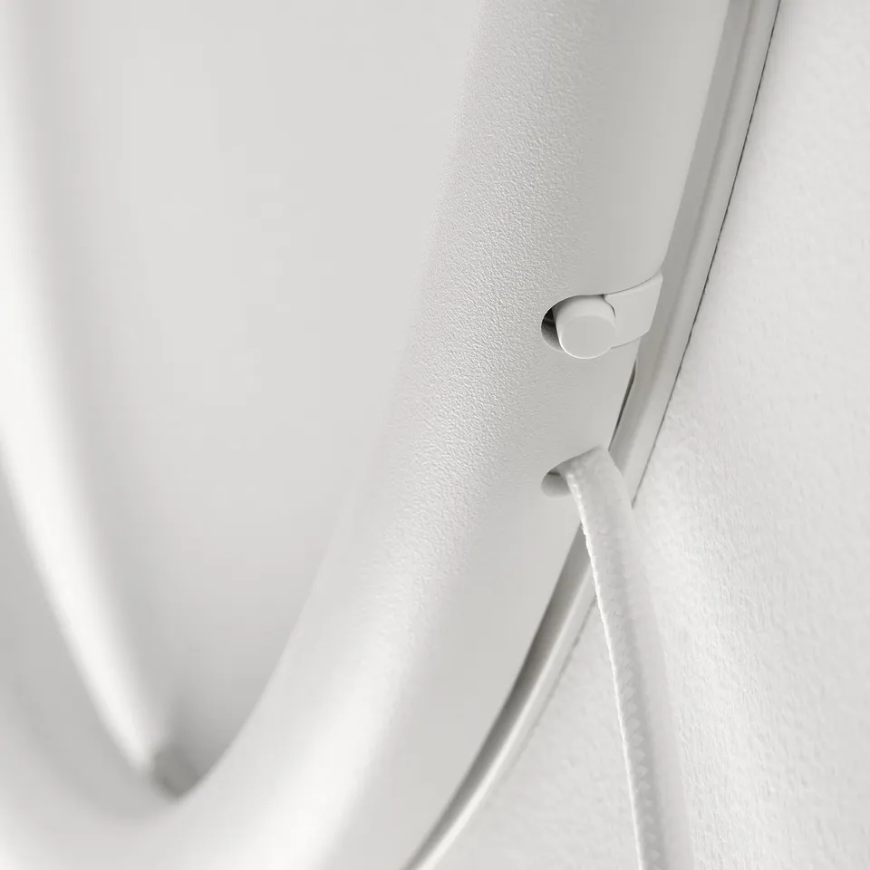 White minimalist wall lamp with sleek, curved design and clean finish. Close-up of switch button and cable, highlighting modern and refined quality.