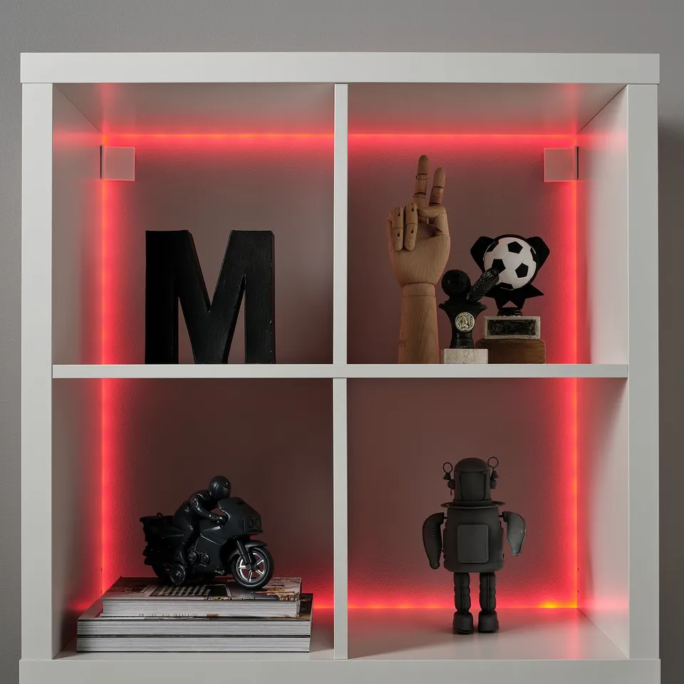 White shelf with red led lights. Displays large letter m, wooden hand, trophy, motorcycle model, and robot figure.