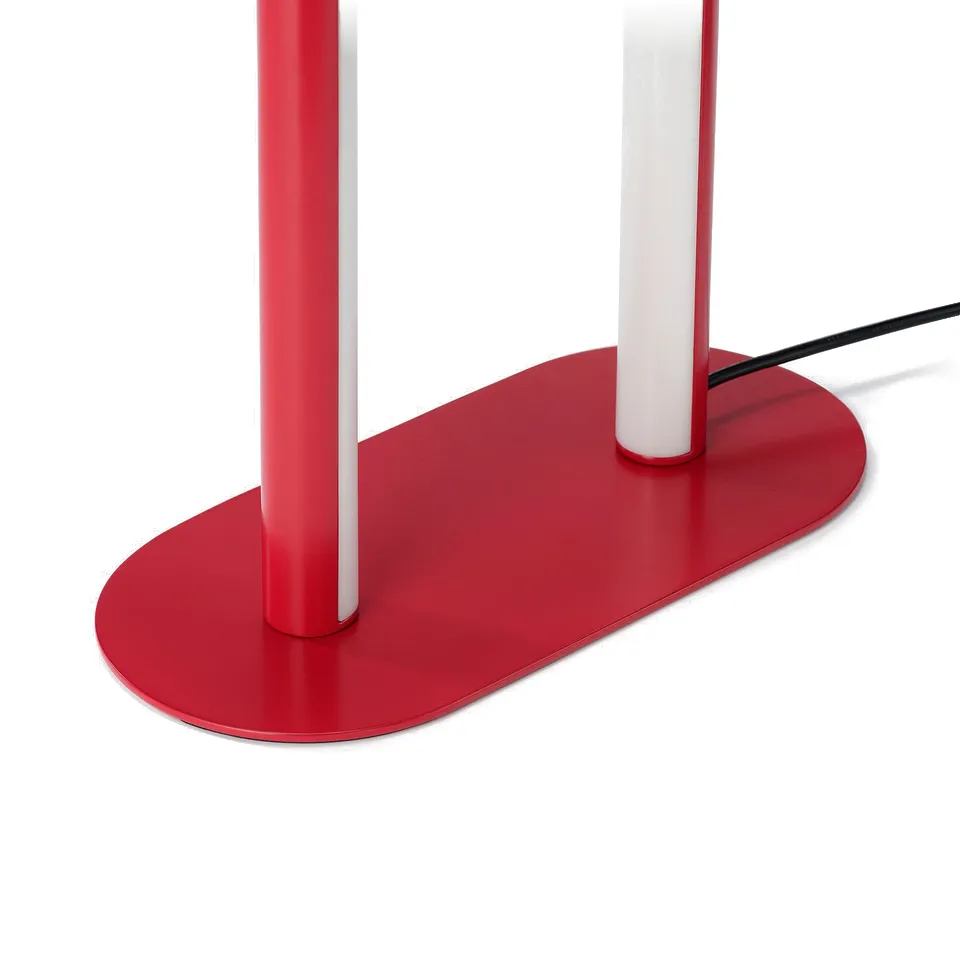 Red modern floor lamp with a sleek white shade stands on an oval red base.