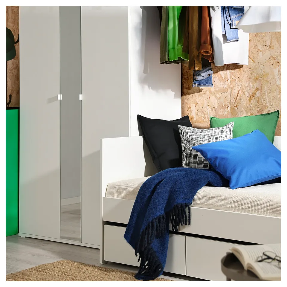 Modern bedroom with VIHALS bed, colourful pillows, blue blanket, and wardrobe in grey.