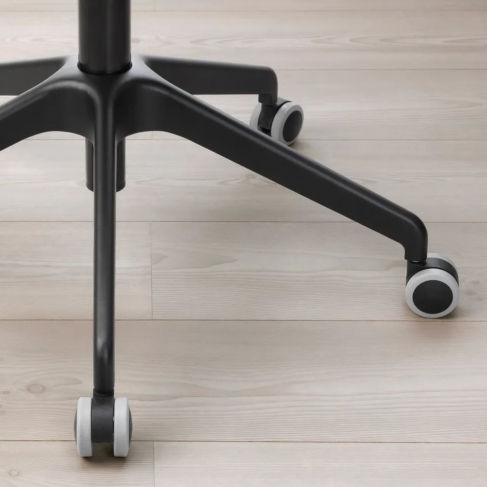 Close-up of a black office chair base with sturdy casters on a wooden floor.