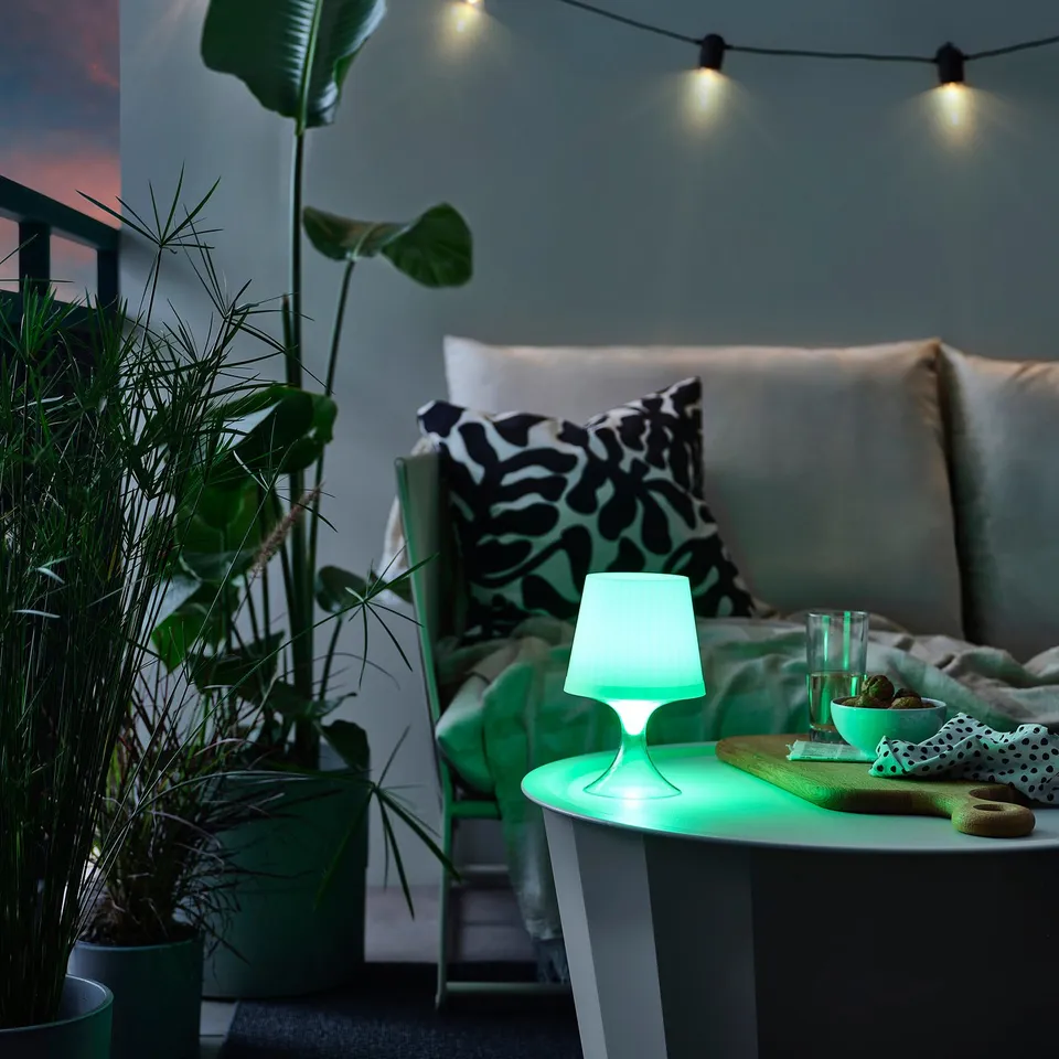 Modern LAMPAN lamp in light green on coffee table with plants and furniture.