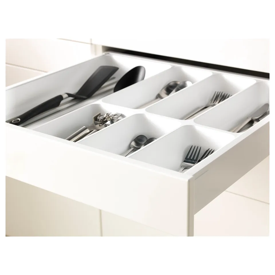 White kitchen drawer organised with sections for cutlery and utensils, including forks, spoons, knives, and kitchen tools.