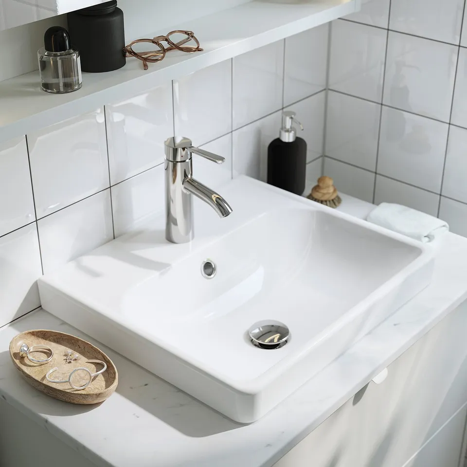 Modern bathroom sink with tap, subway tiles, tornado drain, tray with jewellery and soap dispenser.