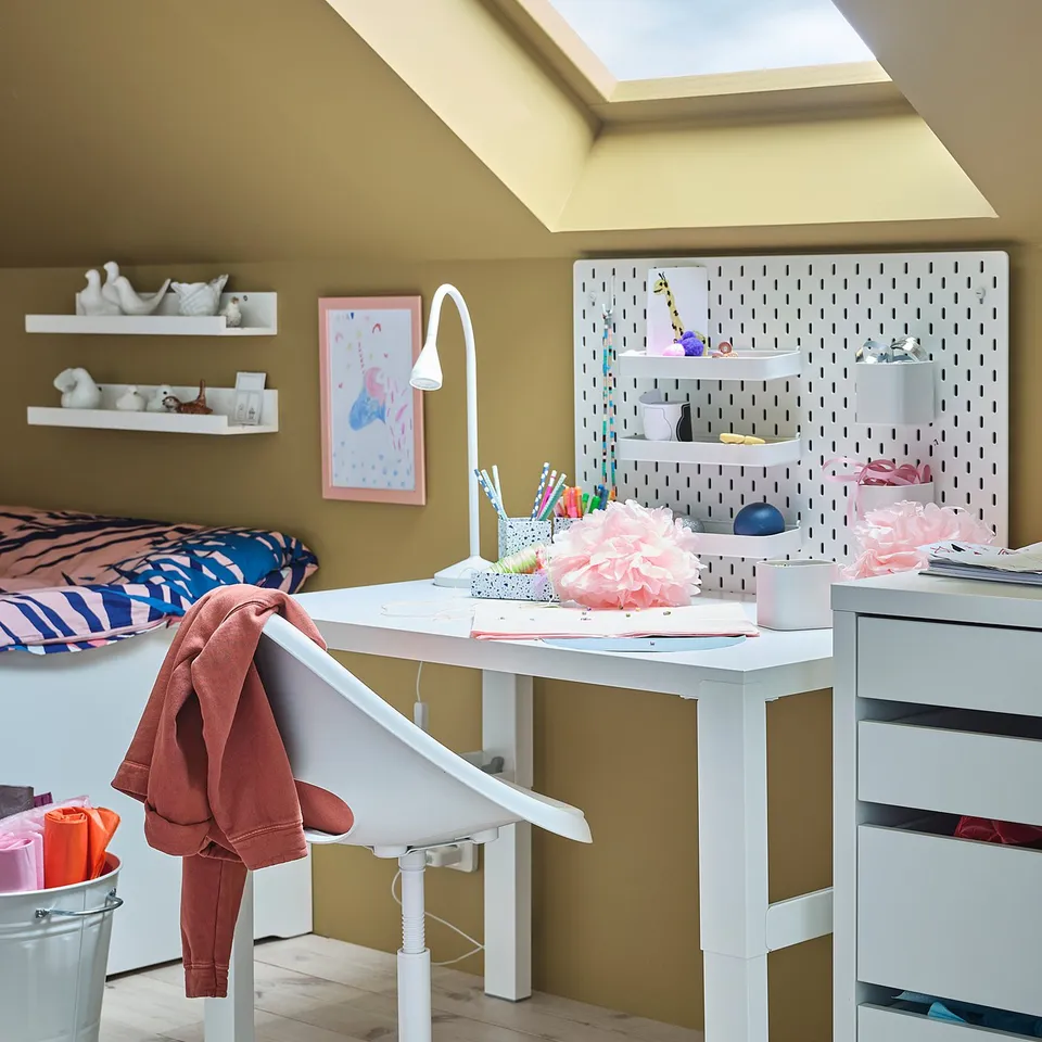 Childs study area with LOBERGET chair, desk, & pegboard. Art supplies on desk.