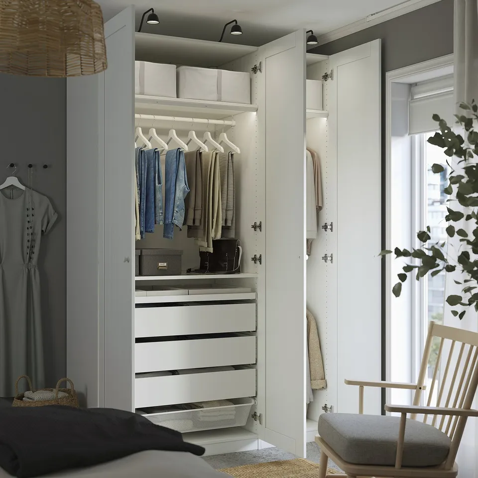 Bedroom with open closet showing clothes, shelves, and drawers. Two lamps illuminate the wardrobe.