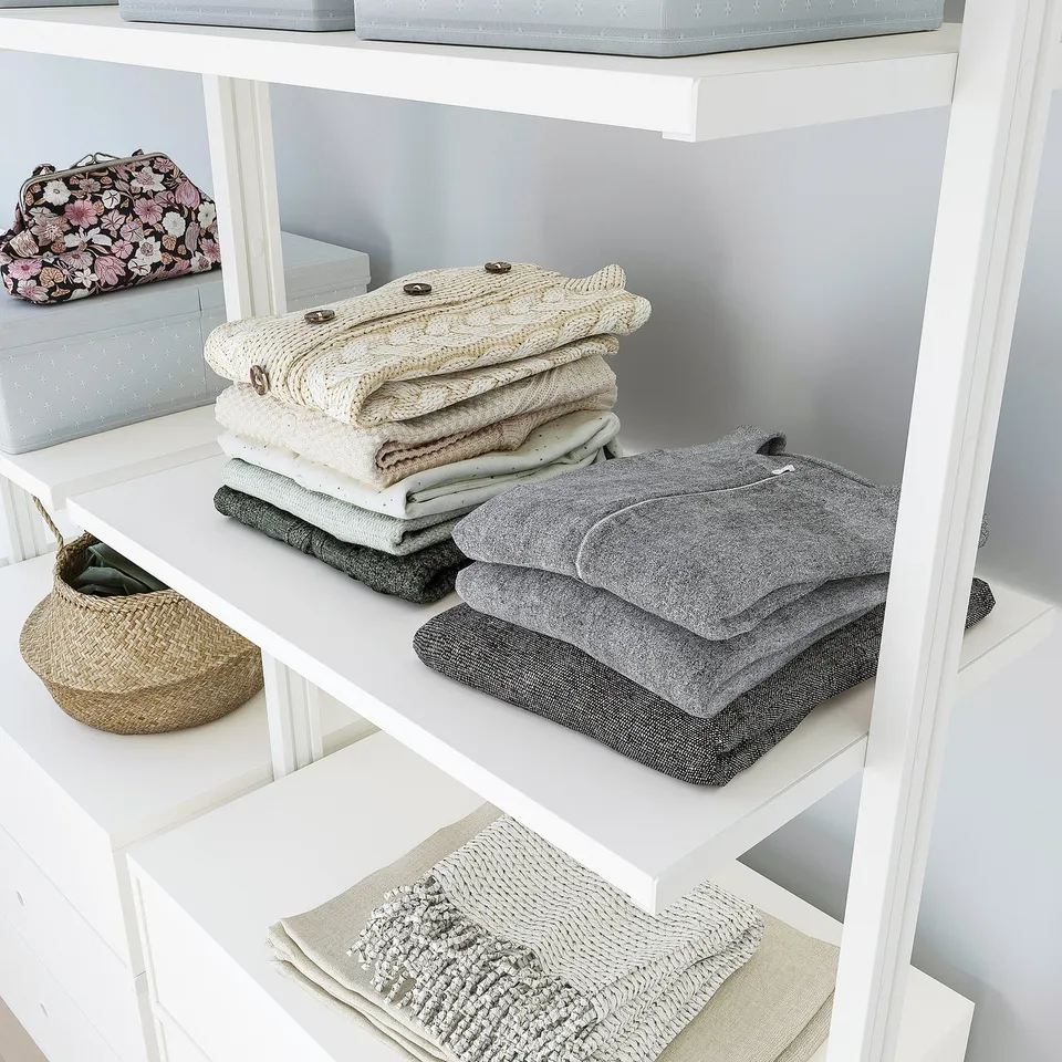Folded clothes and accessories organised on adjustable white shelves.