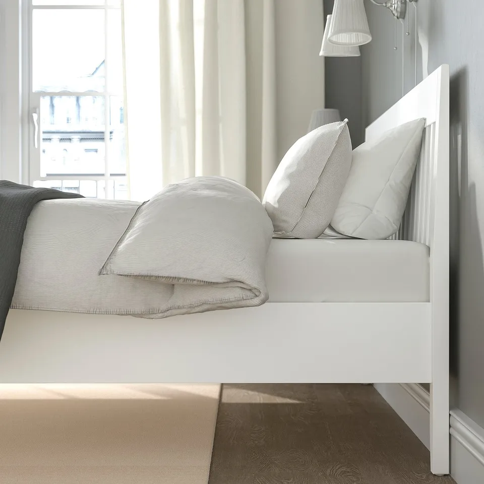 Bed frame with adjustable sides, centred headboard, and slatted base visible in the bright, clean bedroom setting.