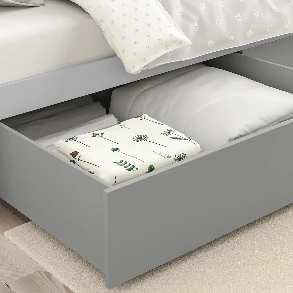 Grey bed with open storage drawer showing floral bedding.