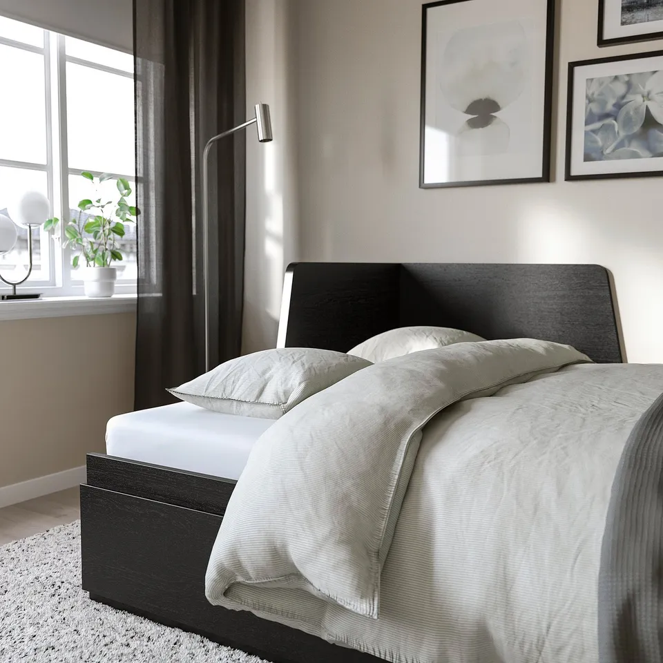 Black day-bed with white bedding, storage drawers, near window.