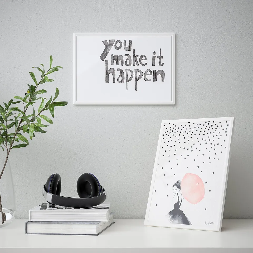 Desk with books, plant, headphones, two inspirational art prints.