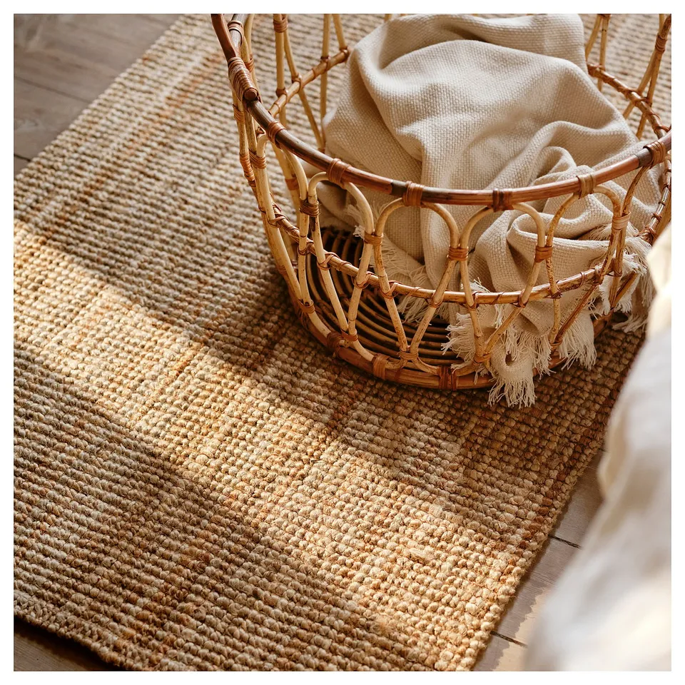 Rattan basket with white cloth on beige jute rug.