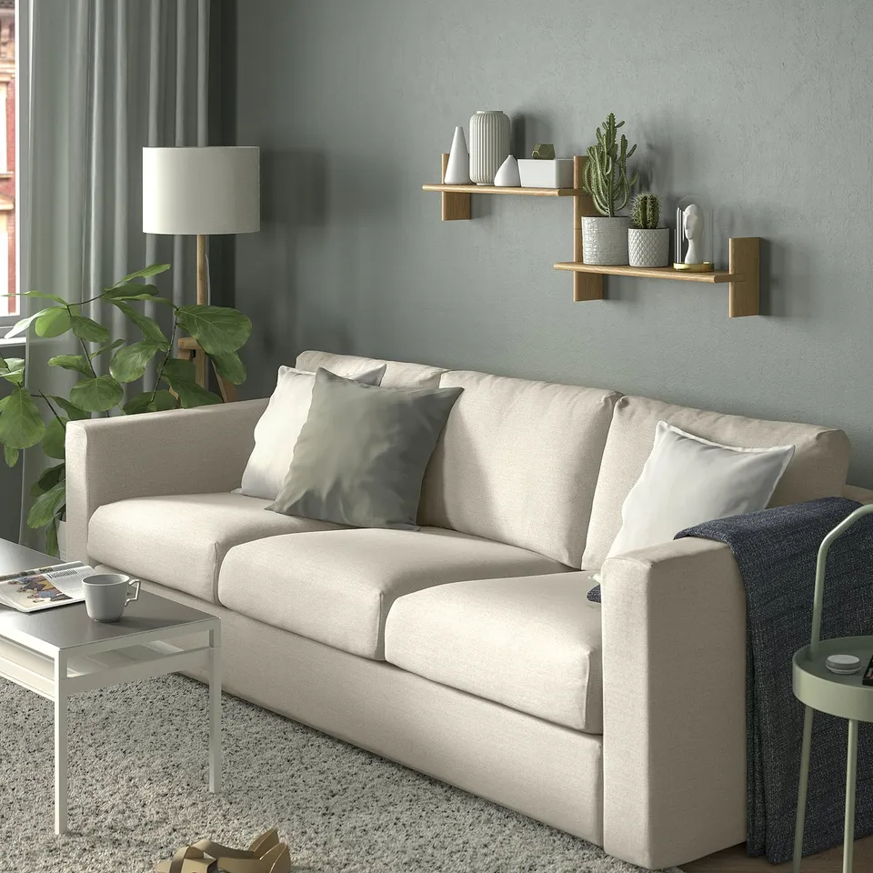 Cosy living room with wall shelf. Beige sofa, pillows, plants, lamp, warm decor.