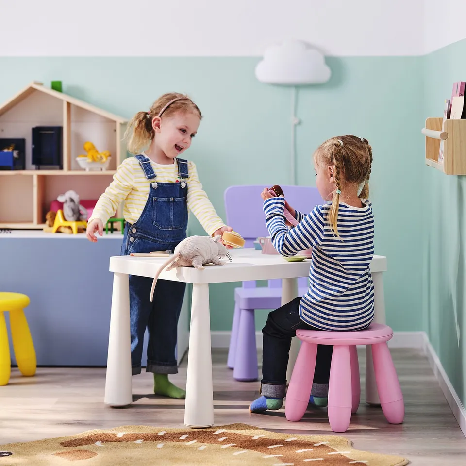Two kids playing with toy food at a small, white table, ages 3-6. Lightweight, easy clean, indoor/outdoor use.