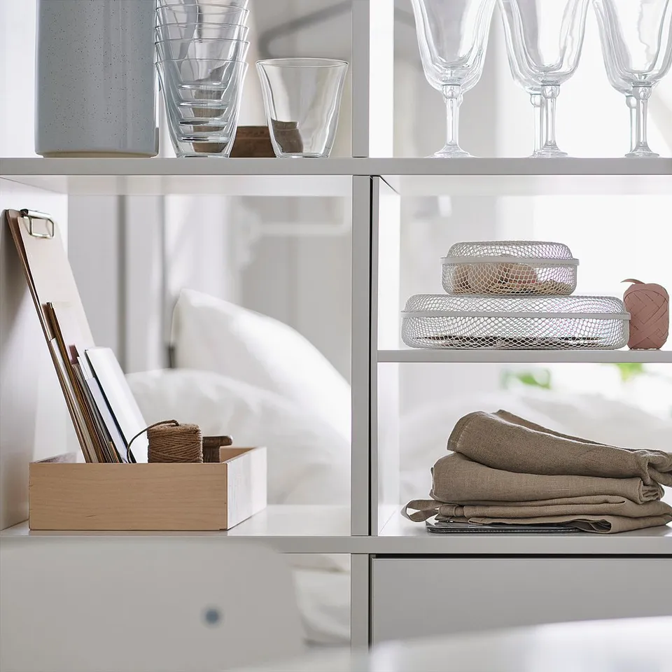 White KALLAX shelves display glassware, folded linens, and dishes neatly.
