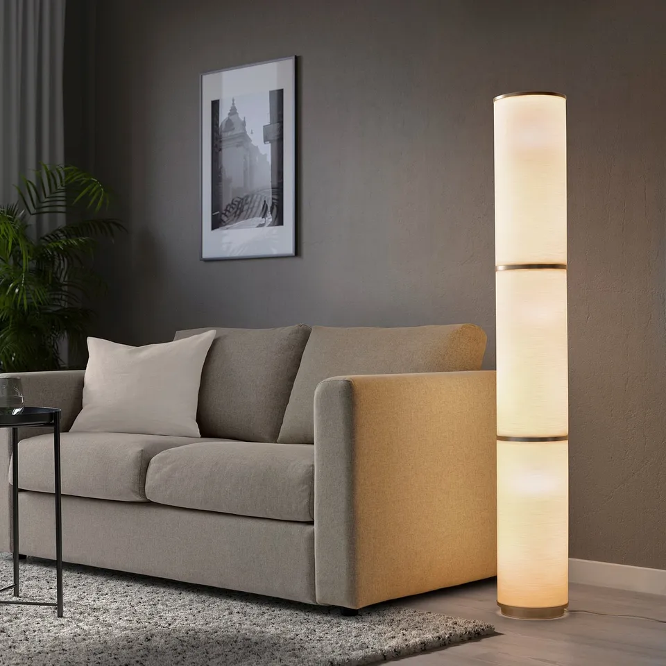 Modern living room with high VIDJA floor lamp, grey couch, black coffee table, and wall artwork.