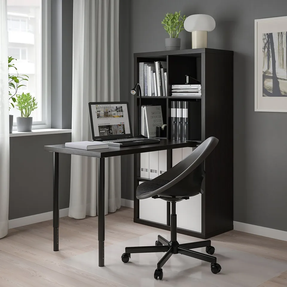 Black KALLAX shelving unit with a laptop, chair, and decor. Modern, minimalist design suitable for small spaces.