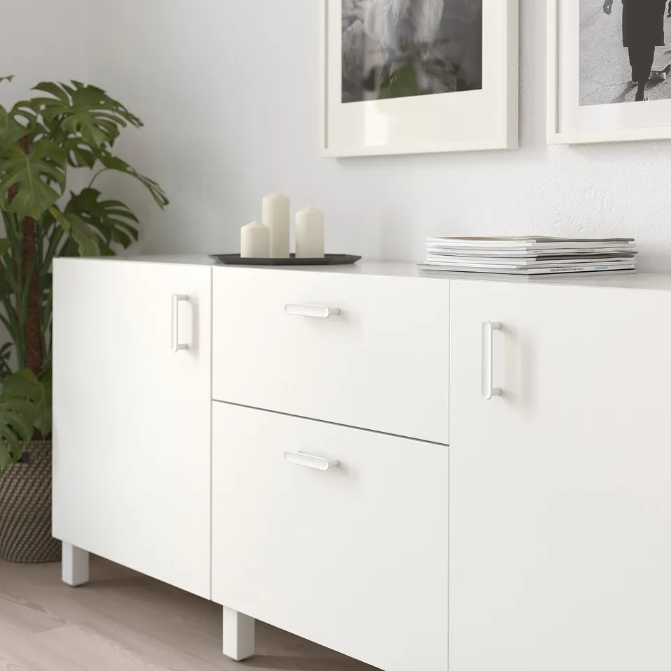 White cabinet with drawers and doors, adorned with candles and magazines, jazzed up with modern knobs and handles.