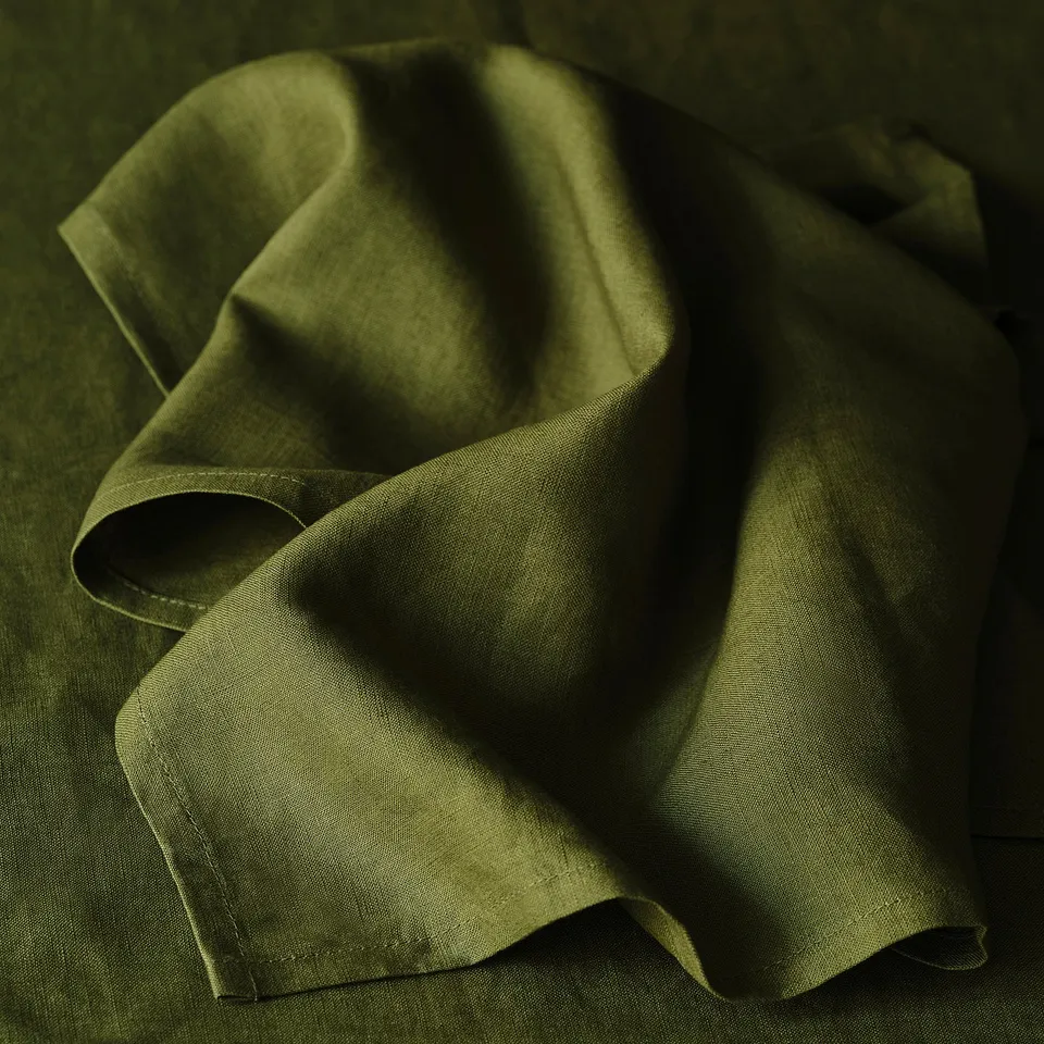 Close-up of neatly folded green linen napkins, smooth texture, even stitching.