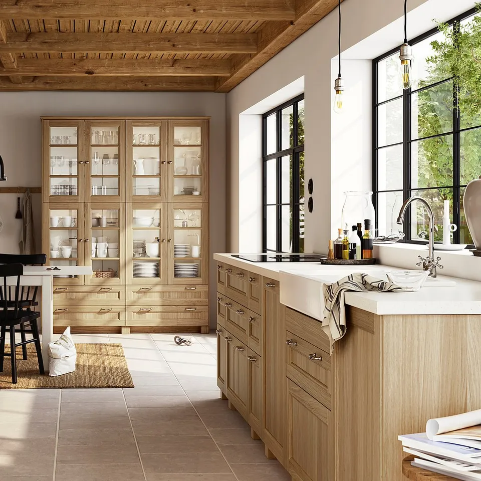 Spacious kitchen with light wood cabinets, black chairs, and large windows, featuring VEDHAMN oak details and modern appliances.