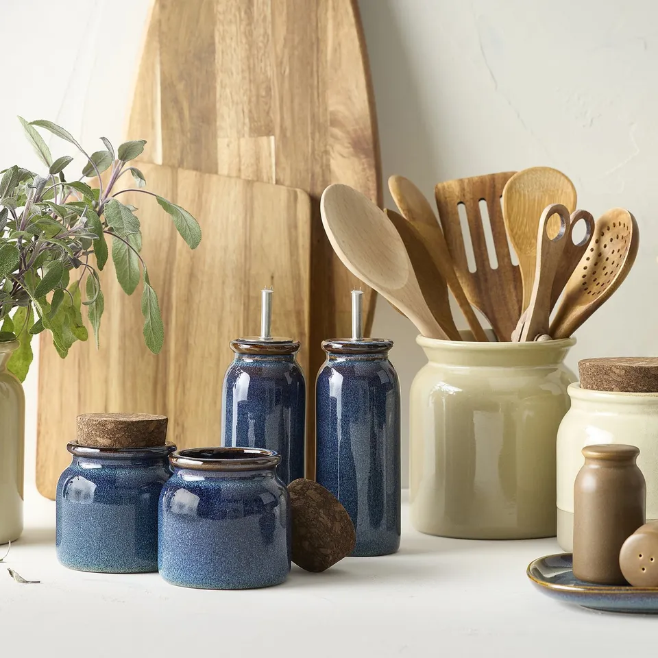 Blue BRUGDHAJ jars in stoneware with cork lids, displayed with wooden utensils and cutting boards.
