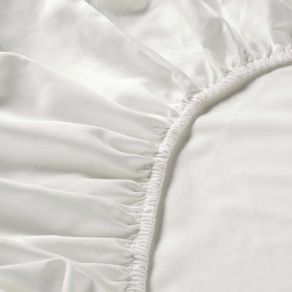 Closeup of white, soft bed sheet with smooth texture and elastic edge.