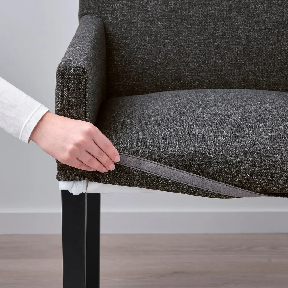 Hand lifting STRANDTORP chair seat, revealing removable, washable cover for easy cleaning.