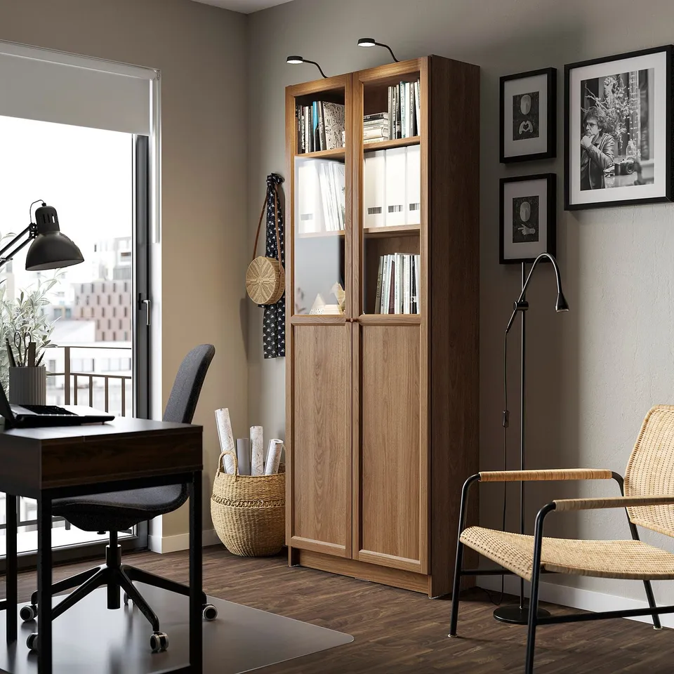 Home office with BILLY bookcase, wooden, tall, glass doors, desk, chair, window, city view.