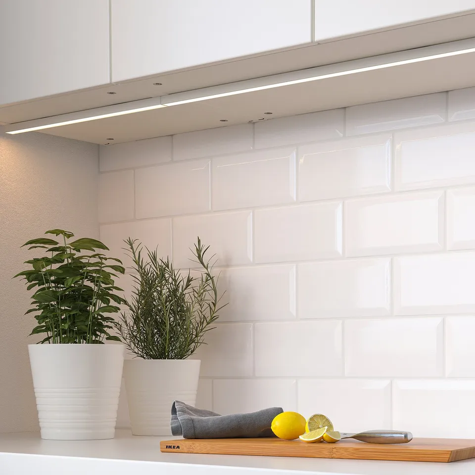 Modern kitchen with under-cabinet lighting, plants, and lemons on the countertop.