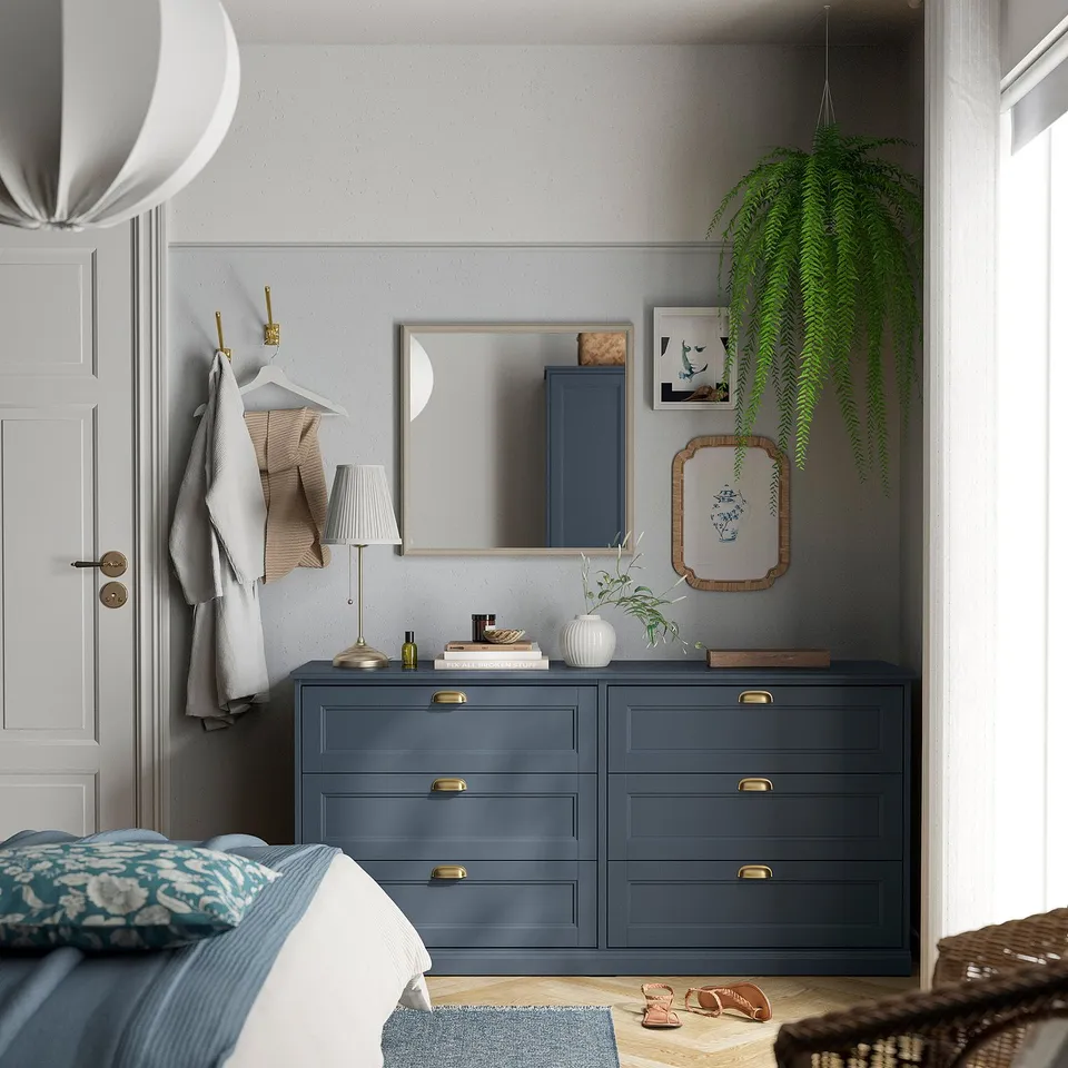 Cosy bedroom with grey dresser, gold handles, mirror, & blue accents.