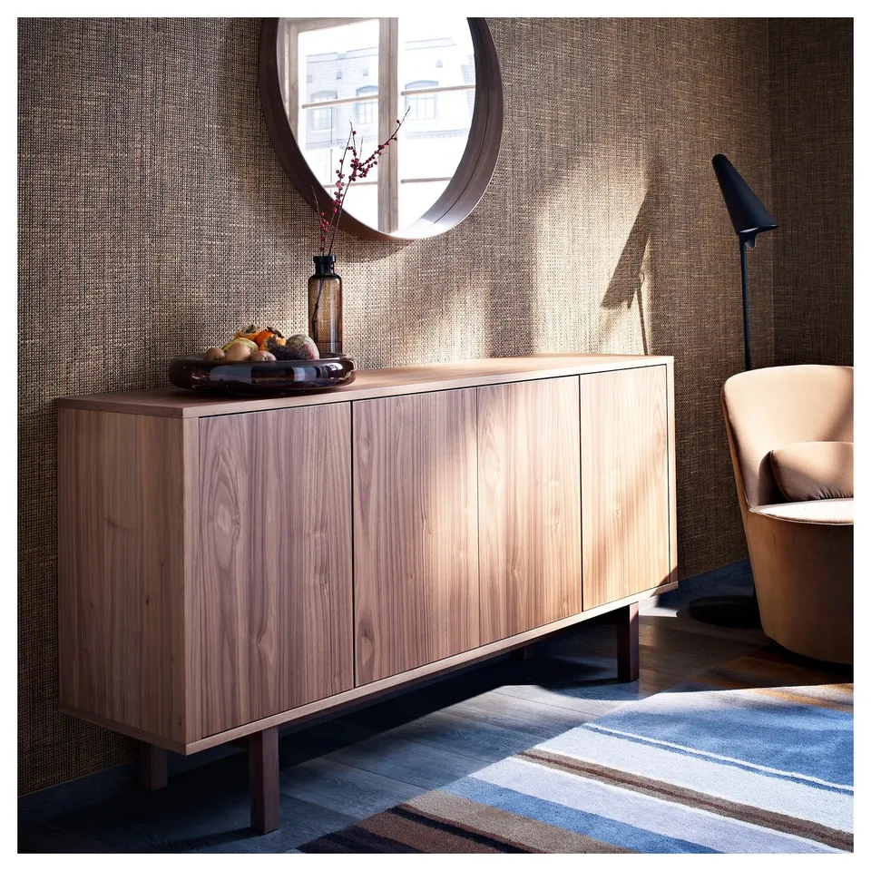 Modern living room with beech sideboard, round mirror, striped rug, and beige chair.