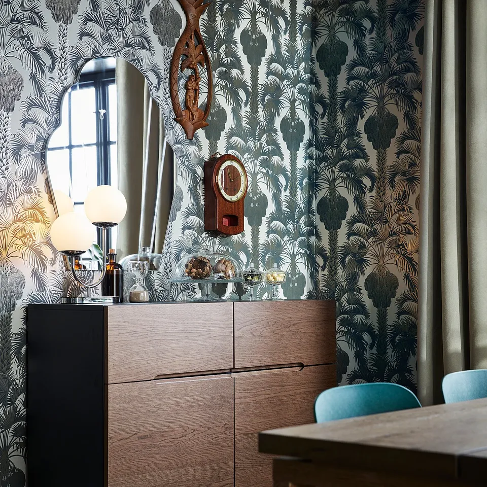 Modern dining room with KLACKENÄS sideboard, globe lamp, and blue chair.