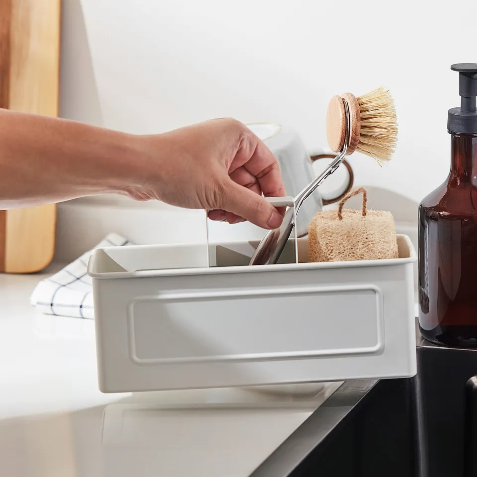 Hand placing dish brush into VÄLVÅRDAD organiser by sink.