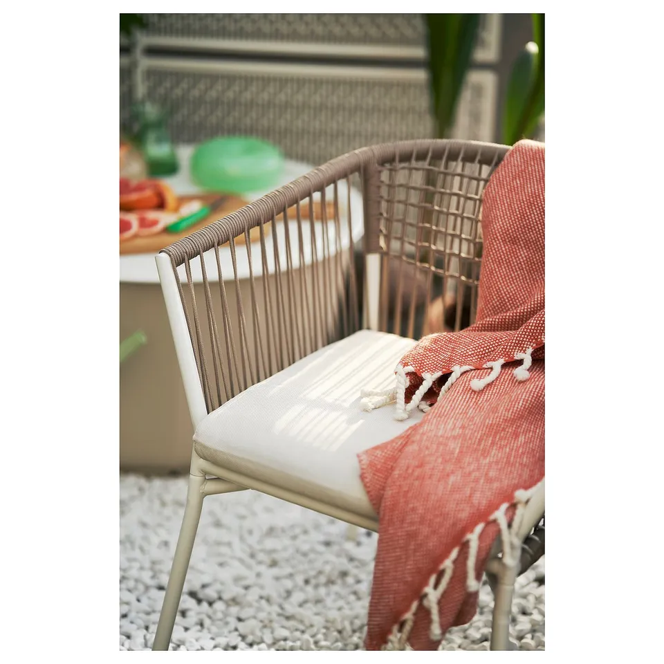 Thats a brown SEGERÖN wicker chair with a white cushion. Its designed for outdoor use, adding a cosy touch to patios or balconies.
