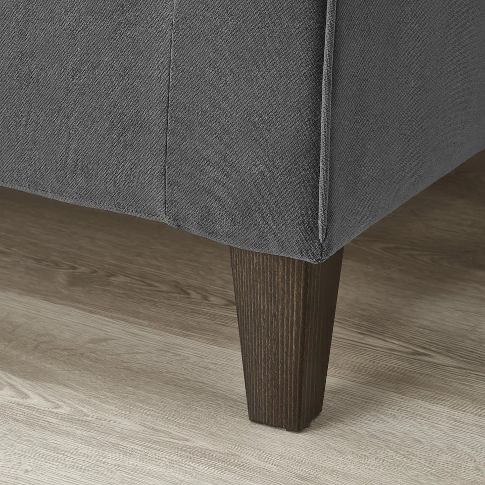 Are grey sofa corner, wood floor visible. Soft cover, sturdy dark leg shown, comfy & durable.
