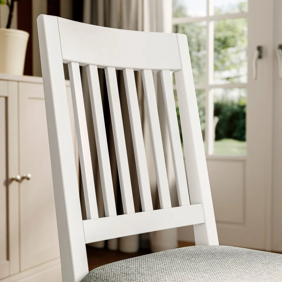 White wooden chair with slatted back; cosy, cushioned seat; clean, modern design.