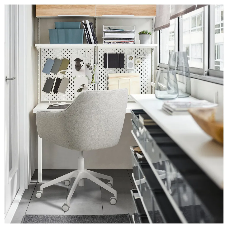 Modern home office: grey chair, white castors, pegboard, desk, window, vases.
