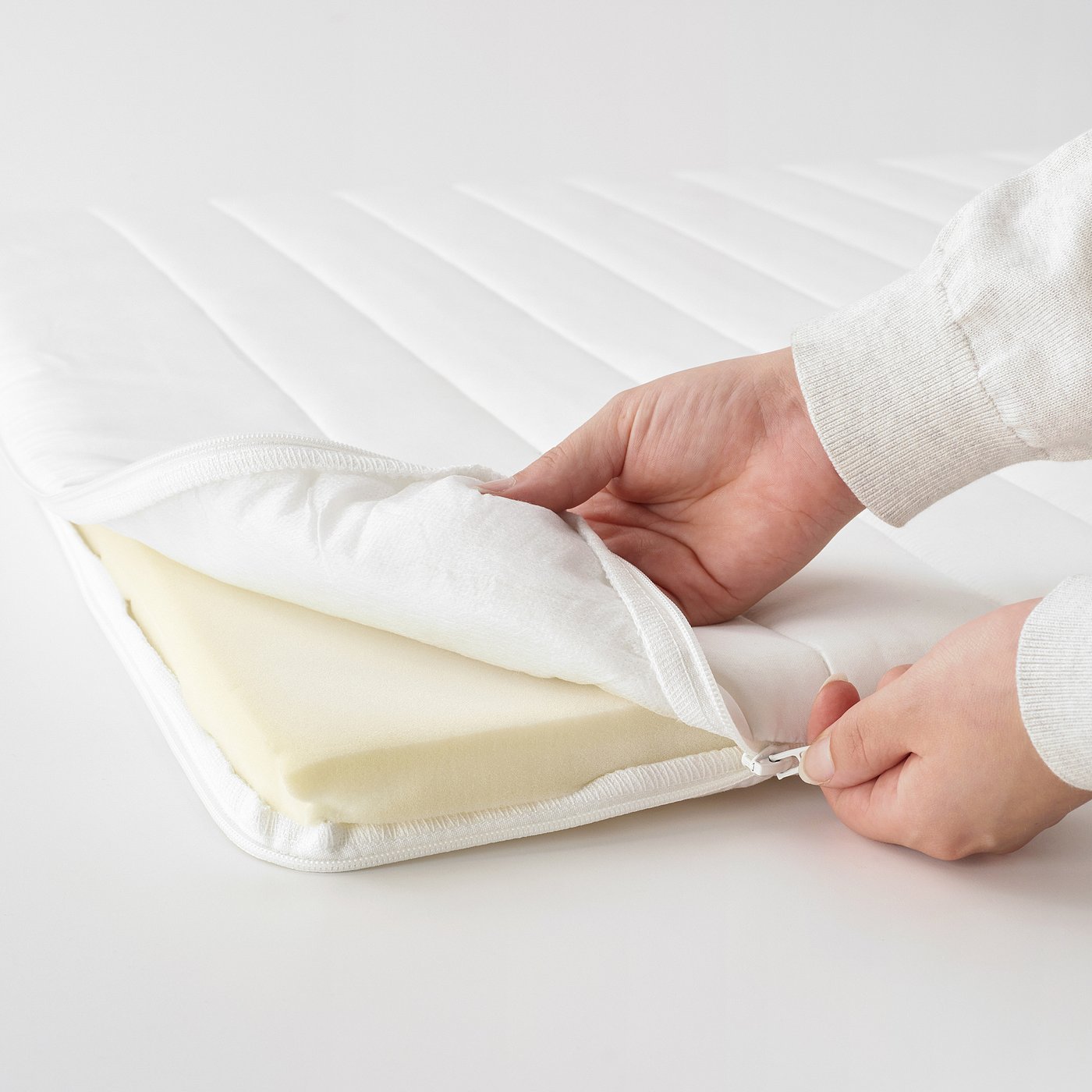 Person opening a rolled mattress, showcasing the supportive pocket spring design for back sleepers.