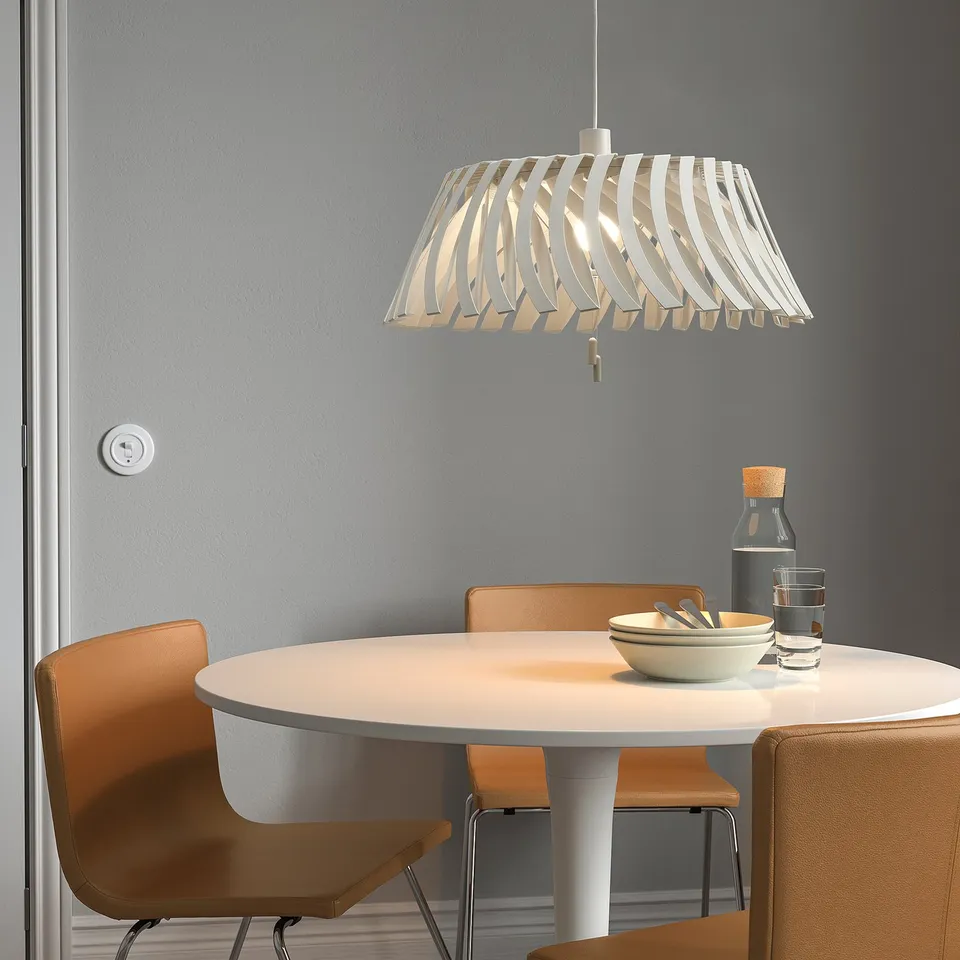Pendant lamp YTLÄGE white, adjustable design, hangs over small dining table with chairs.