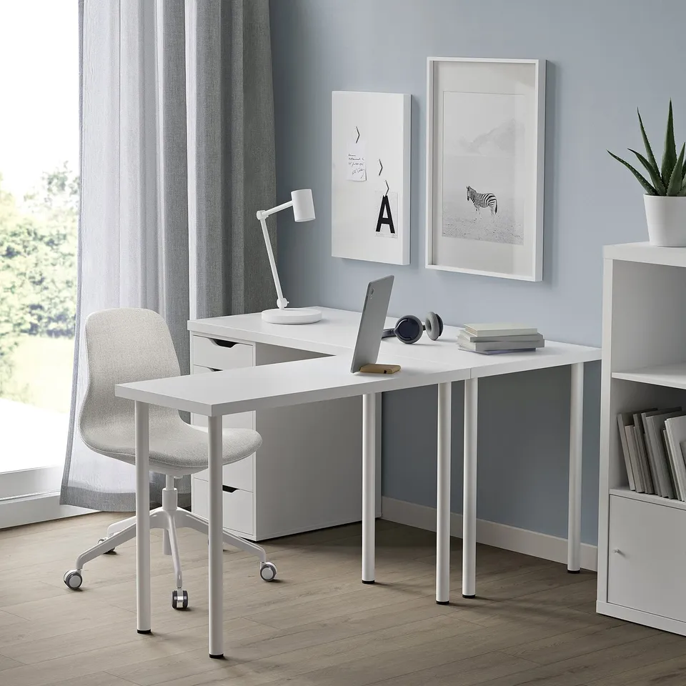 Modern white desk setup with chair, lamp, laptop, and bookshelf.