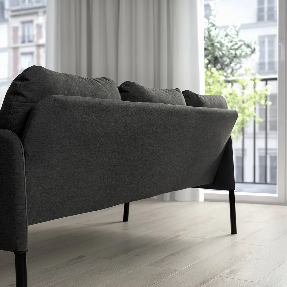 Modern compact GLOSTAD sofa in dark grey fabric with sleek metal legs, perfectly fitting small spaces.