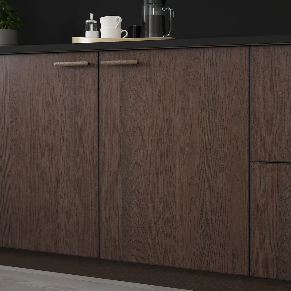 Dark wood kitchen cabinets with two visible doors, sleek handles, and minimalist knobs. Top shelf holds mugs, a coffee maker, and other items.