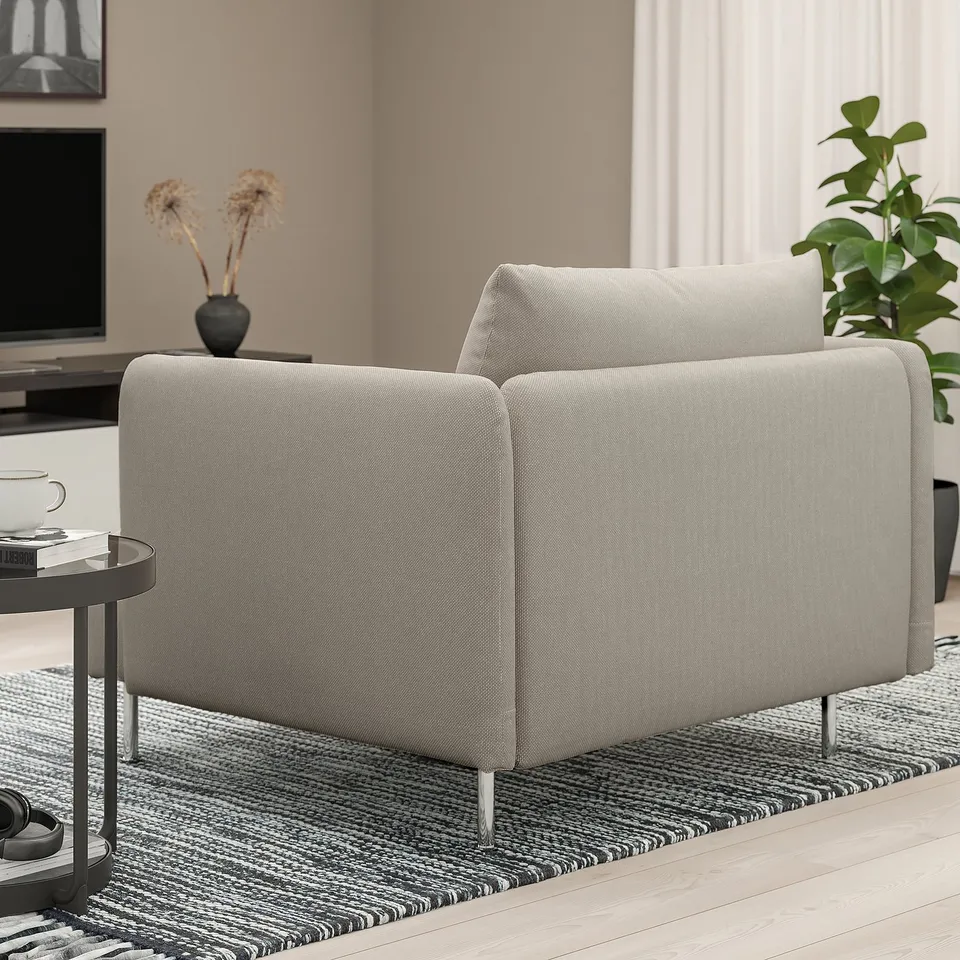 Grey SÖDERHAMN sofa with deep seats and loose cushions. High-leg design, sleek and comfortable. Left side table with mug, book, headphones.
